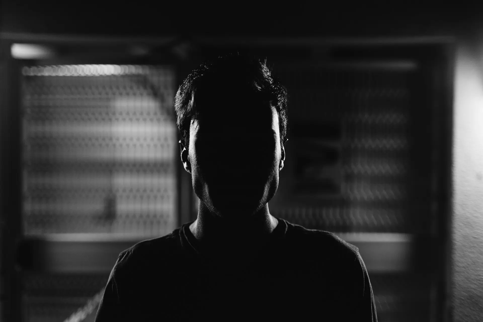 A figure in silhouette against a lit window, in black and white