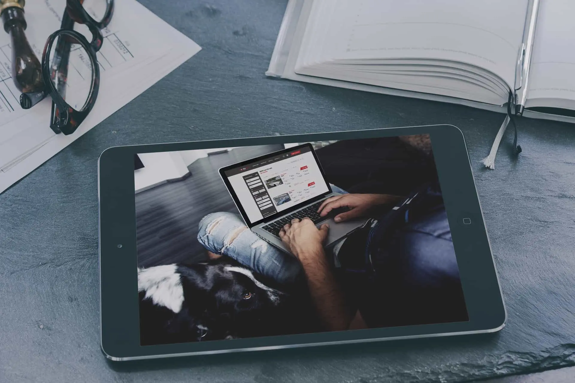 A tablet on a desk showing a BlogMyCars listing page