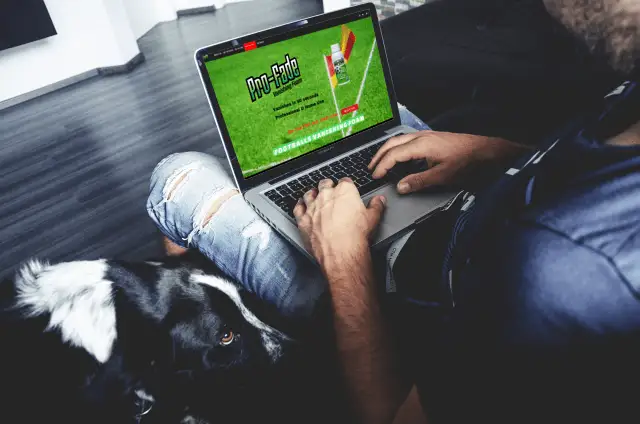 Someone browsing the Pro-Fade site on a laptop, a dog beside them